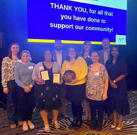 Group of volunteers holding award in front of screen